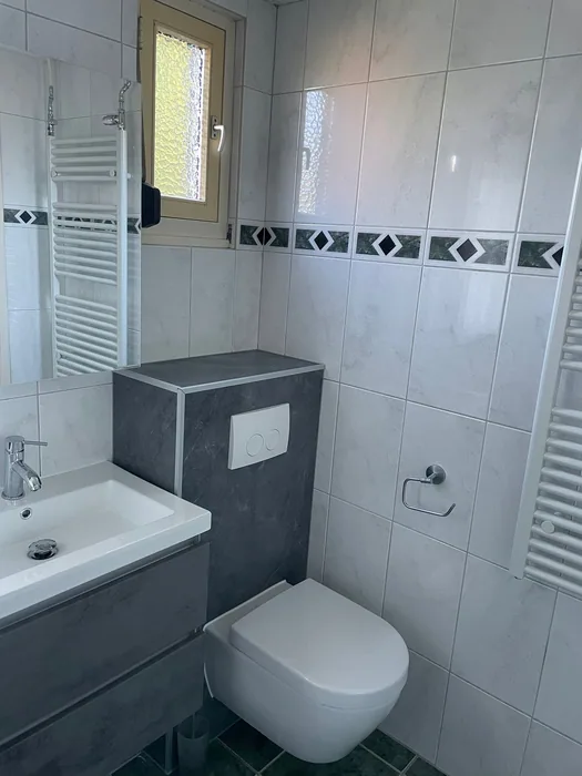 Hangtoilet tegen een antraciet voorzetwand naast een grijs wastafelmeubel