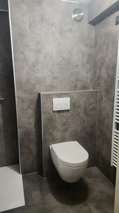 Wit hangtoilet met drukplaat op een voorzetwand met grijze betonlook wandpanelen