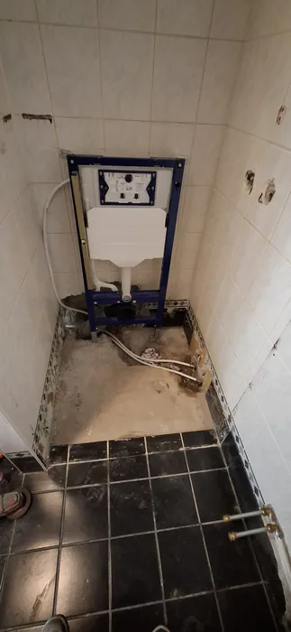 Inbouwreservoir in een betegelde hoek, met de vloer rond de afvoer opengemaakt