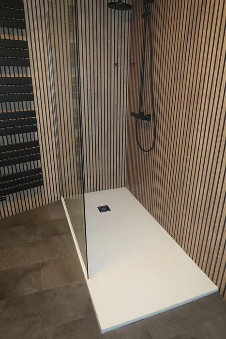 Inloopdouche met witte douchebak, zwarte regendouche en houten lamellenpanelen in dezelfde woning