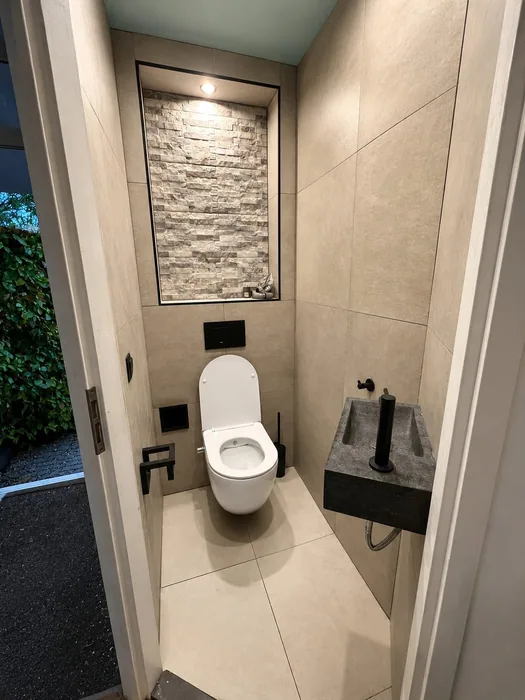 Toilet met hangtoilet, natuurstenen fonteintje en een verlichte nis met steenstrips