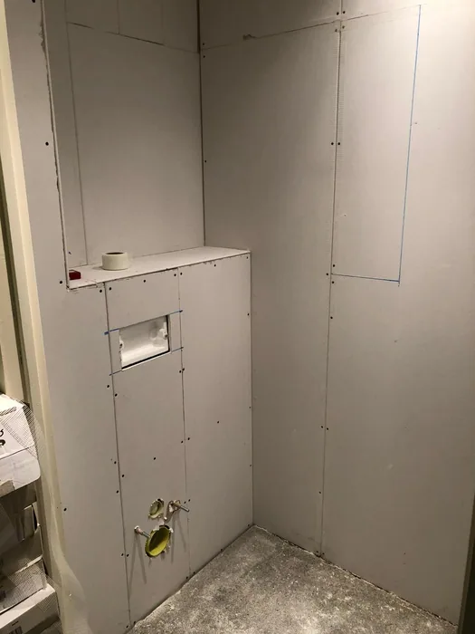 Dezelfde toiletruimte tijdens het werk: nieuwe voorzetwand met opening voor de drukplaat en aansluitingen