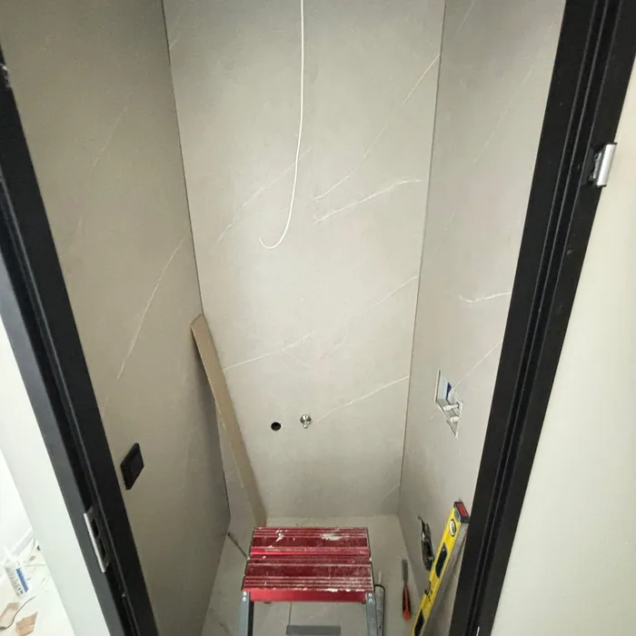 Smalle toiletruimte met nieuwe lichte marmerlook wandpanelen, nog zonder sanitair